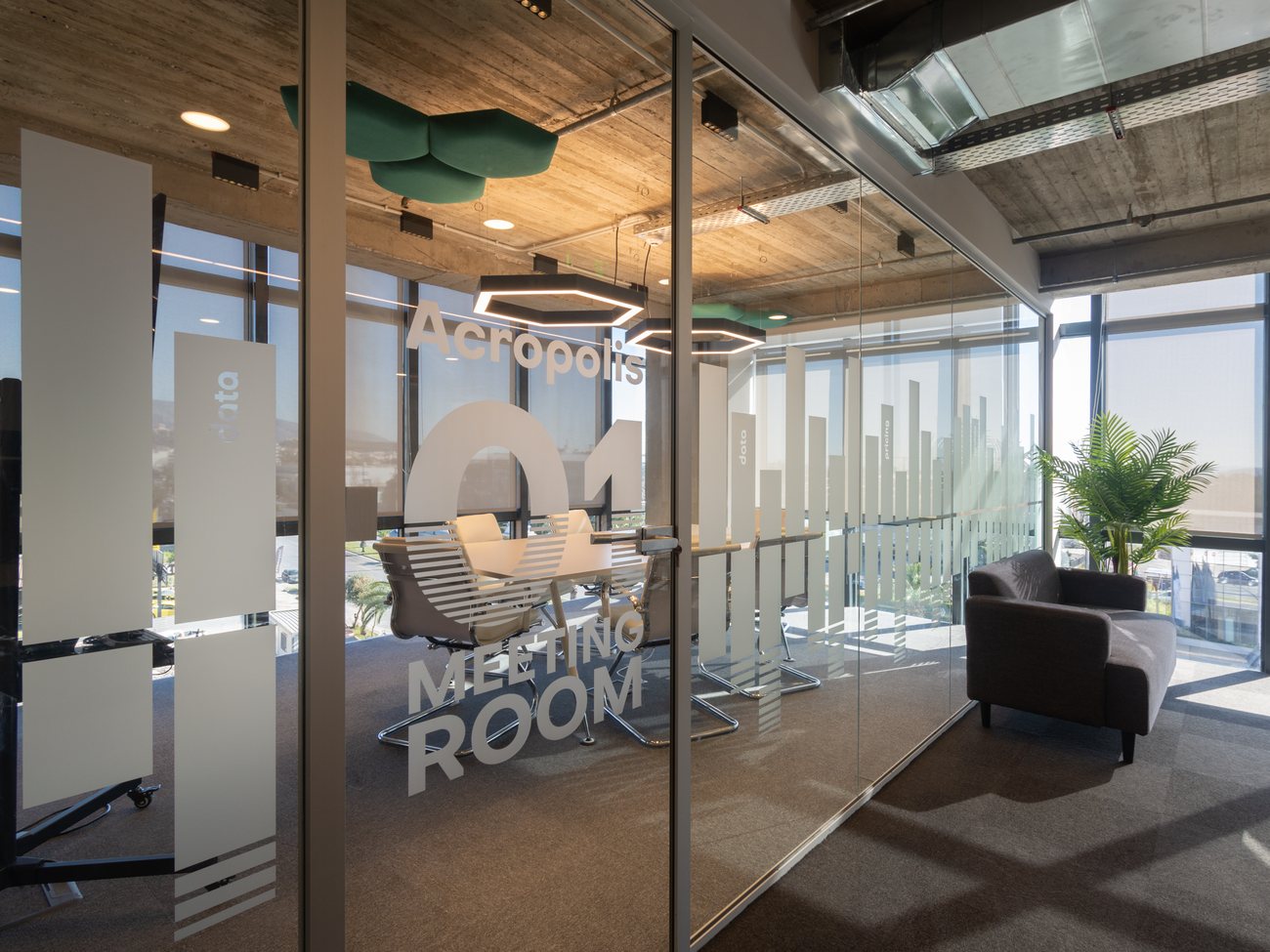TGN Data offices, Athens — glazed meeting room with hexagon lighting under an exposed concrete slab, AKPRAXIS office fit-out