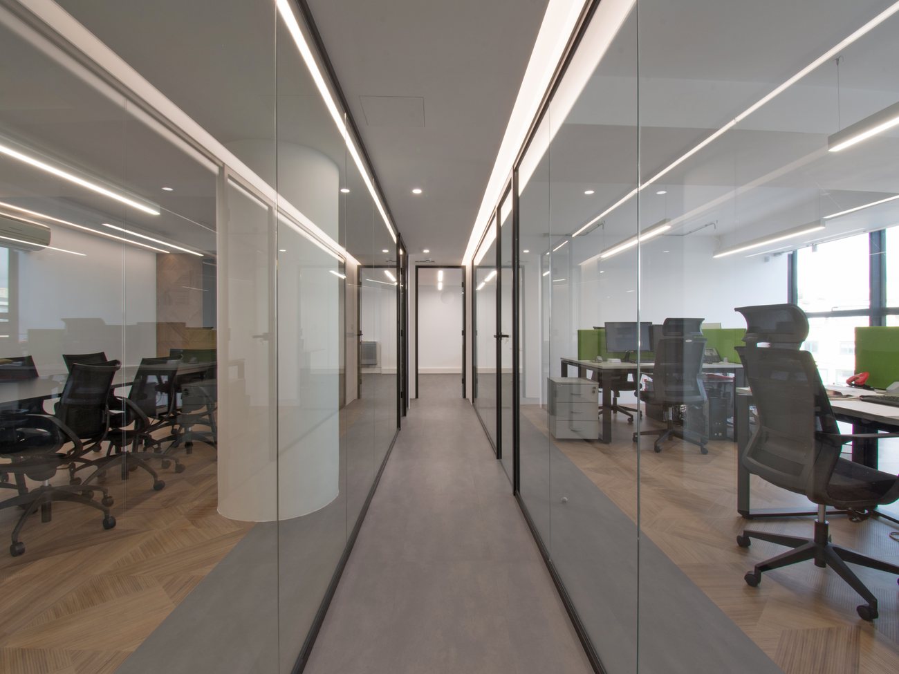 INNEWS offices, Athens — glazed office corridor with herringbone oak floors and linear lighting, AKPRAXIS office fit-out